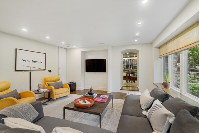 living area with arched walkways, baseboards, recessed lighting, and wood finished floors