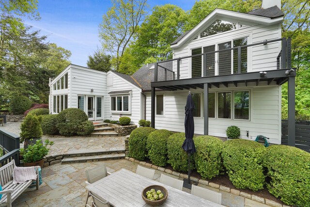 rear view of property with entry steps, a patio, a balcony, a chimney, and french doors