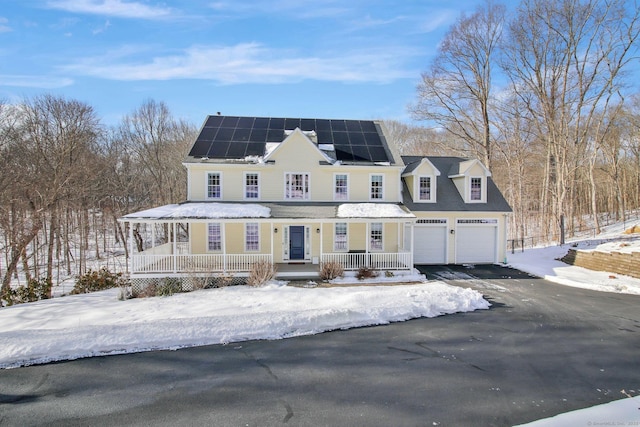 view of front of home with aphalt driveway, a porch, and solar panels