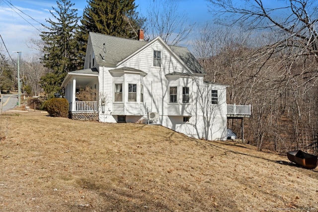 view of front of home featuring covered porch, roof with shingles, a front lawn, and a chimney