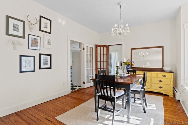 dining room featuring a chandelier, baseboards, hardwood / wood-style floors, and baseboard heating