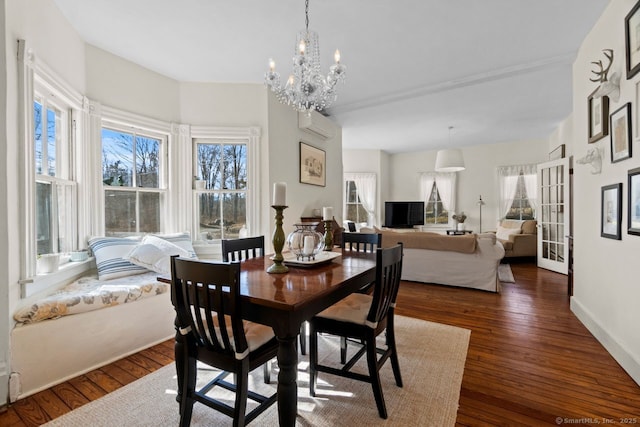 dining space featuring a chandelier, an AC wall unit, hardwood / wood-style floors, and baseboards