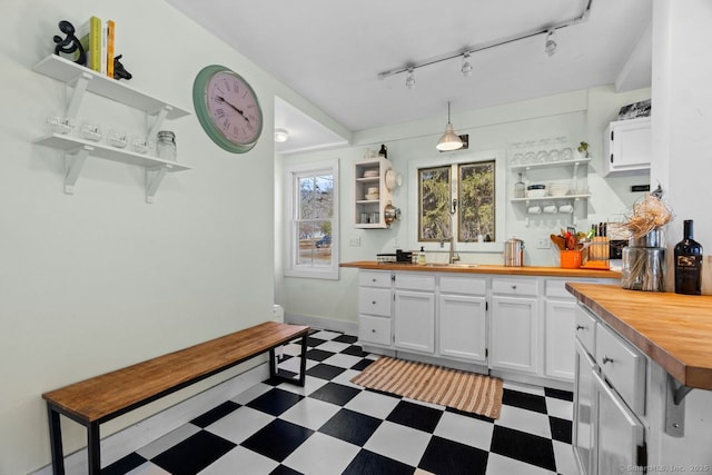 kitchen with dark floors, butcher block counters, white cabinetry, and open shelves