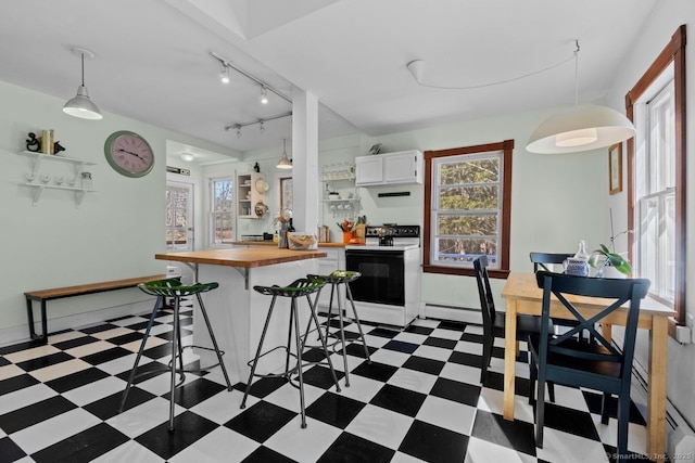 kitchen with electric range, wood counters, a breakfast bar area, light floors, and white cabinetry