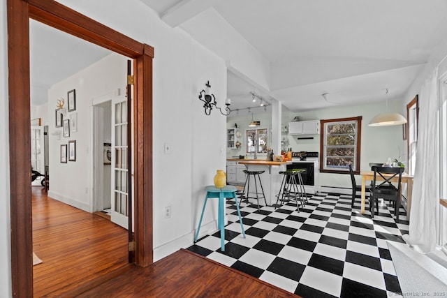 interior space with dark floors, a peninsula, white cabinets, baseboards, and electric range oven