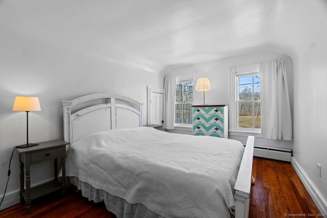 bedroom with a baseboard heating unit, baseboards, and wood finished floors