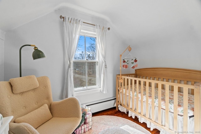 bedroom featuring lofted ceiling, a crib, baseboard heating, and wood finished floors