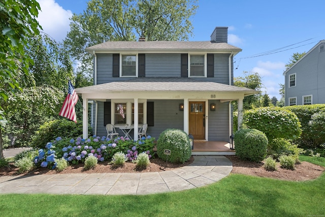 view of front of house featuring a shingled roof, a chimney, and a porch