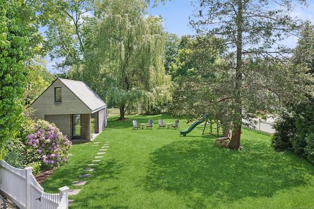 view of yard featuring an outbuilding, a playground, and fence