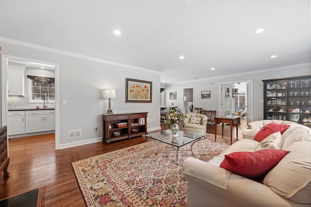 living area with baseboards, visible vents, dark wood finished floors, crown molding, and recessed lighting