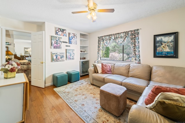 living area with a ceiling fan, a textured ceiling, and light wood-style flooring