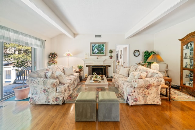 living area featuring vaulted ceiling with beams, wood-type flooring, a fireplace, and visible vents