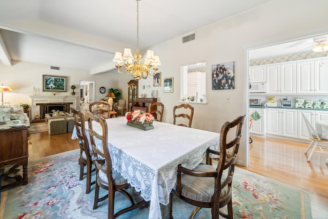 dining area featuring light wood finished floors, visible vents, beam ceiling, and a chandelier