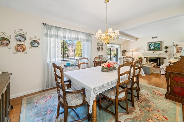 dining room with visible vents, a chandelier, beamed ceiling, wood finished floors, and a fireplace