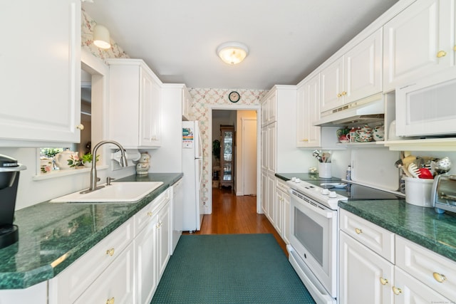 kitchen with a sink, white cabinetry, wallpapered walls, white appliances, and under cabinet range hood
