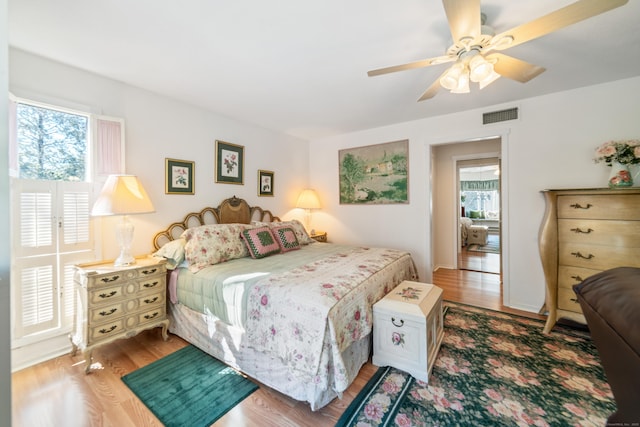 bedroom with a ceiling fan, wood finished floors, and visible vents