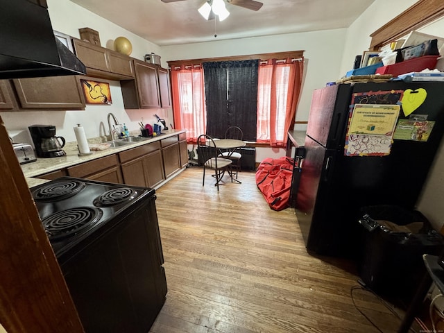 kitchen featuring light wood-style floors, light countertops, black appliances, premium range hood, and a sink