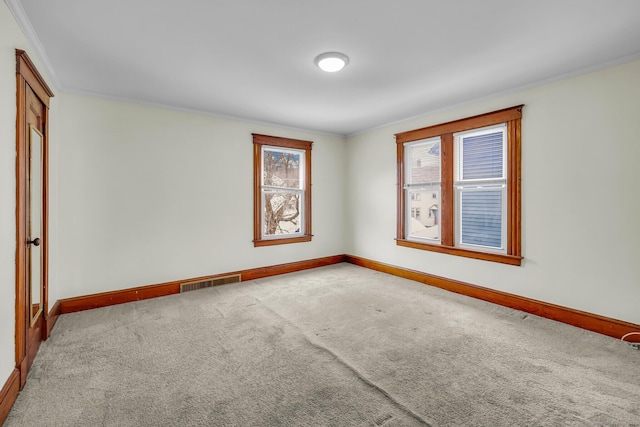 carpeted spare room featuring ornamental molding, visible vents, and baseboards