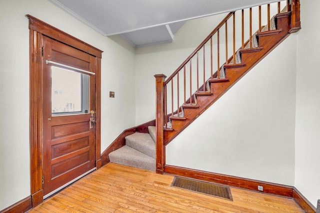 foyer featuring stairs, wood-type flooring, visible vents, and baseboards