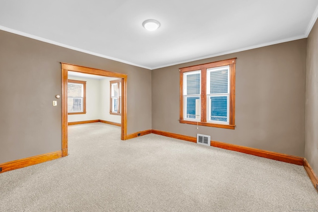 carpeted empty room with ornamental molding, visible vents, and baseboards