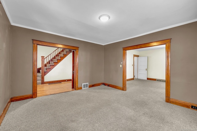 carpeted spare room with baseboards, stairs, visible vents, and crown molding