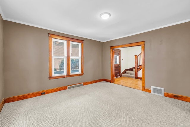 carpeted spare room featuring baseboards, visible vents, and ornamental molding