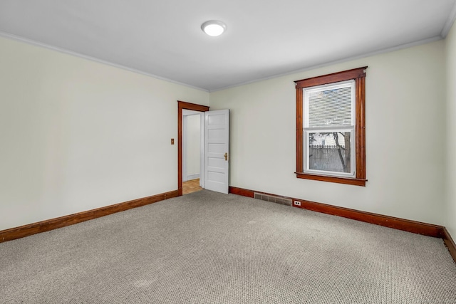 carpeted spare room with visible vents, crown molding, and baseboards