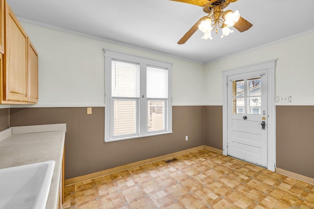 clothes washing area with a wainscoted wall, crown molding, visible vents, a ceiling fan, and a sink