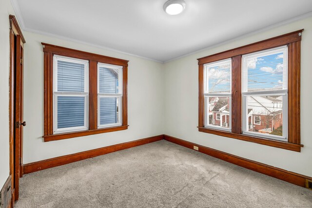 unfurnished room with crown molding, carpet flooring, and baseboards