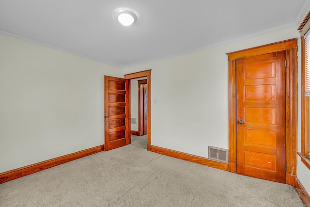 carpeted spare room with ornamental molding, visible vents, and baseboards