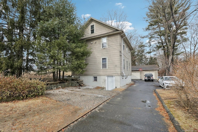 view of home's exterior with a garage, an outdoor structure, and stairs