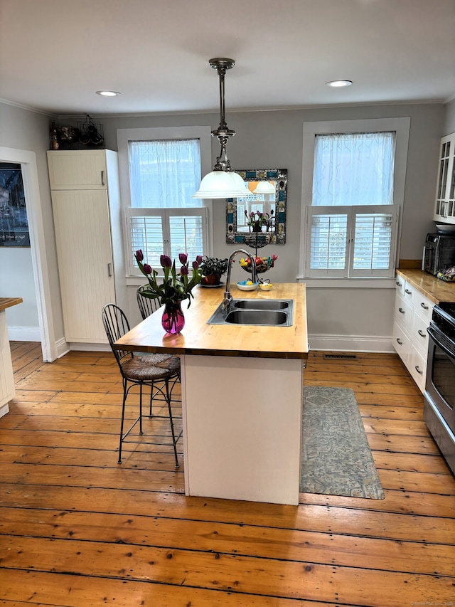 kitchen featuring a breakfast bar area, wood-type flooring, light countertops, white cabinets, and a sink