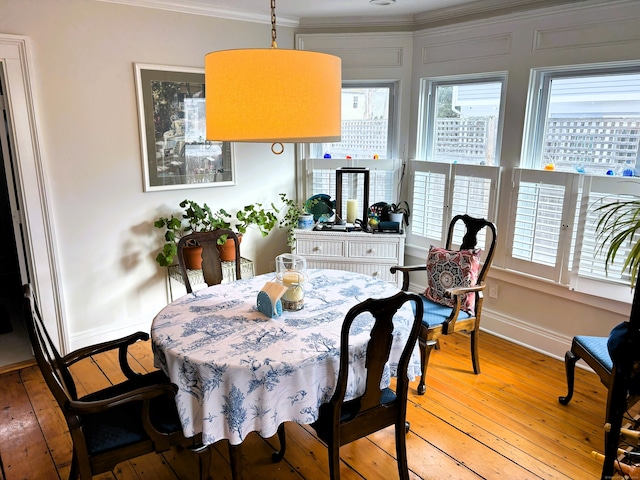 dining space with light wood-style floors, crown molding, and baseboards