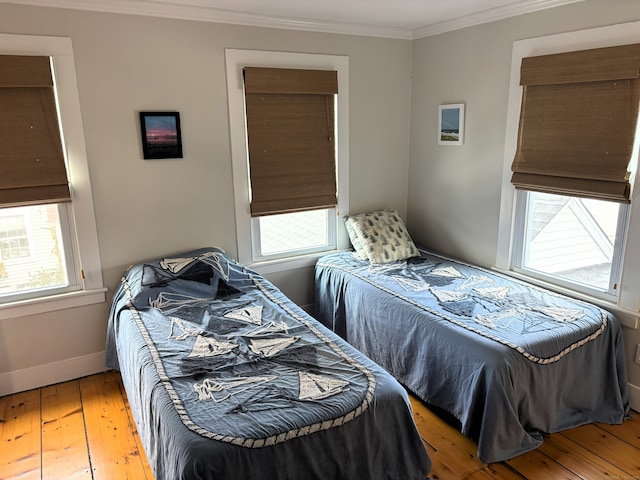 bedroom with baseboards, crown molding, and light wood finished floors