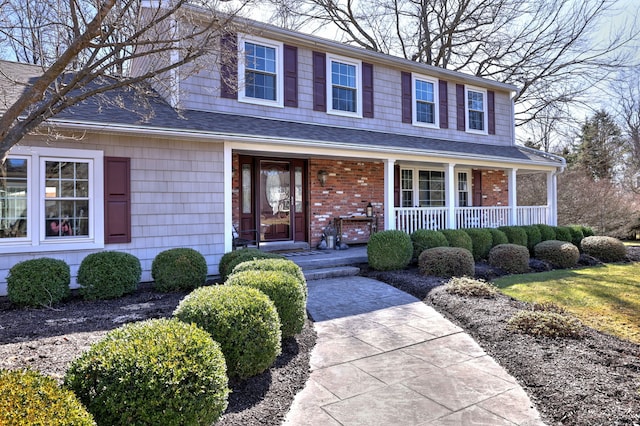 view of front of property with brick siding, covered porch, and a shingled roof