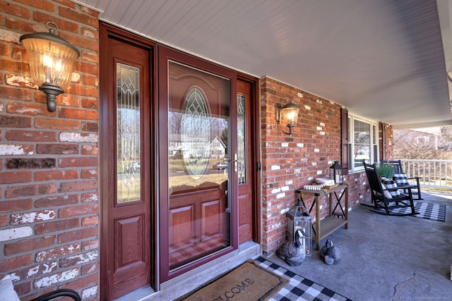 doorway to property featuring brick siding and a porch