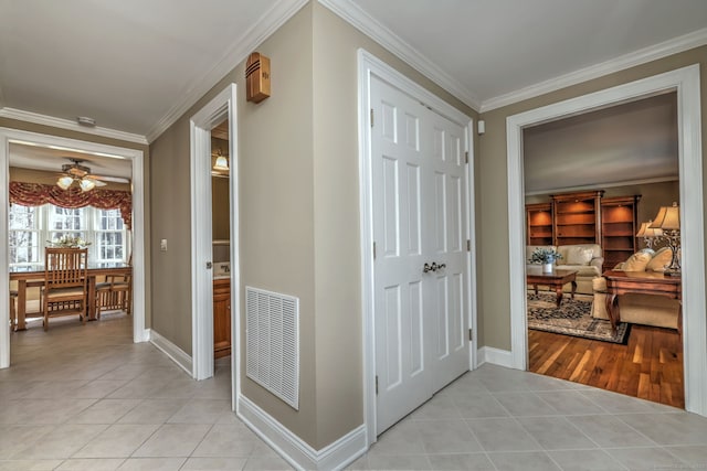 hall featuring crown molding, light tile patterned floors, baseboards, and visible vents