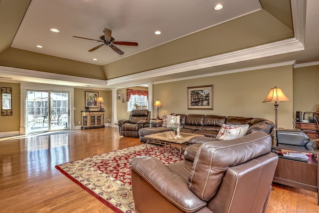 living area with a tray ceiling, decorative columns, crown molding, and plenty of natural light