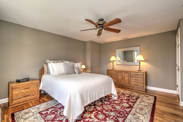 bedroom featuring visible vents, wood finished floors, baseboards, and ceiling fan