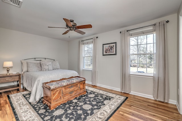 bedroom with visible vents, multiple windows, light wood-style floors, and baseboards