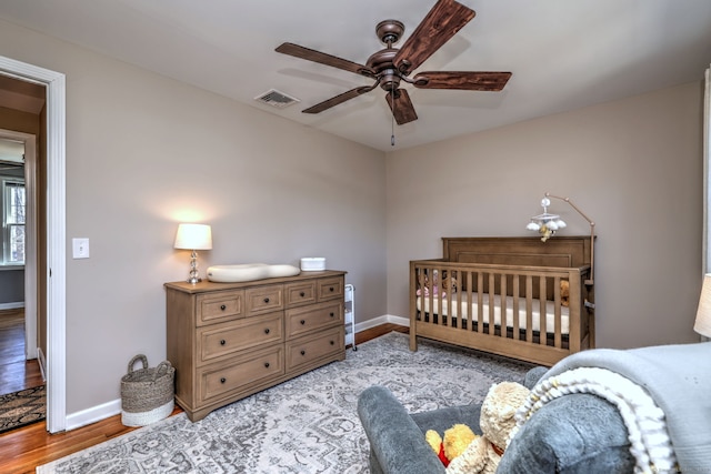 bedroom with visible vents, baseboards, wood finished floors, and a ceiling fan