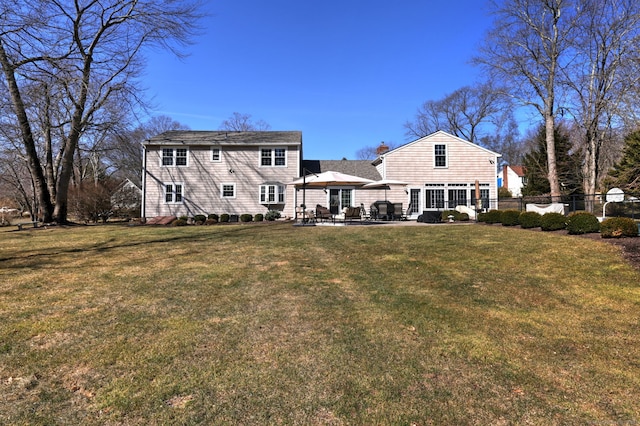 back of property featuring a yard, a patio area, a chimney, and fence