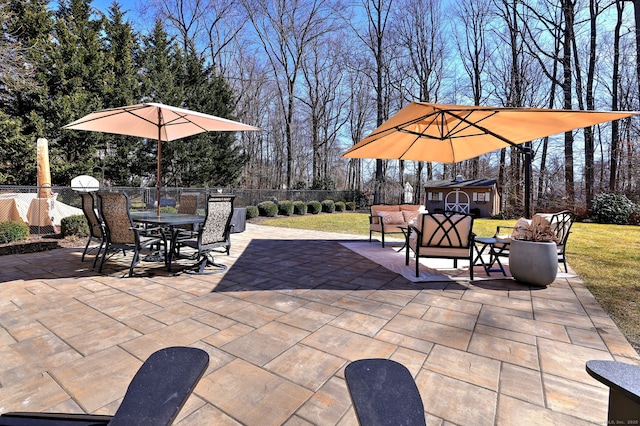 view of patio / terrace with an outbuilding, outdoor dining space, and fence