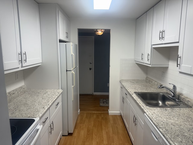 kitchen with white appliances, white cabinets, a sink, and light wood finished floors