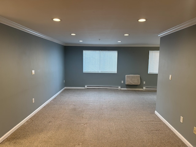 spare room featuring carpet floors, baseboards, baseboard heating, and crown molding