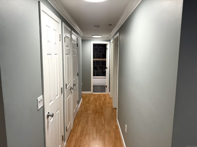 corridor with baseboards, crown molding, and light wood finished floors