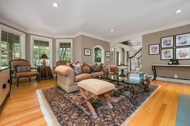 living room with arched walkways, wood finished floors, crown molding, and stairs