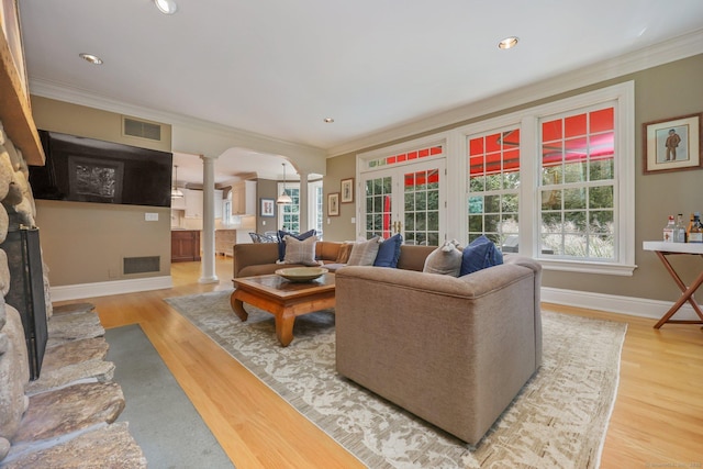 living room with crown molding, visible vents, and decorative columns