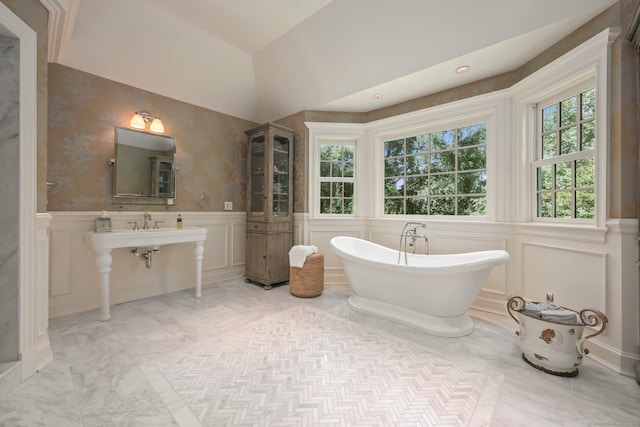 full bath featuring marble finish floor, wainscoting, a freestanding bath, and a decorative wall