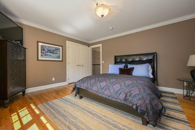 bedroom featuring baseboards, crown molding, and light wood-style floors